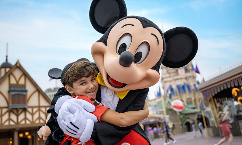 Mickey hugging a child in front of Cinderella Castle