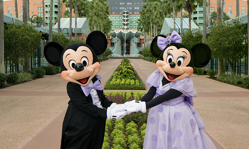 Mickey and Minnie in wedding apparel posing in front of the Walt Disney World Swan and Dolphin causeway